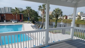 A pool area with a view of a lake and buildings in the background. - Mermaids Retreat Mins to Beach Family Condo (Destin)