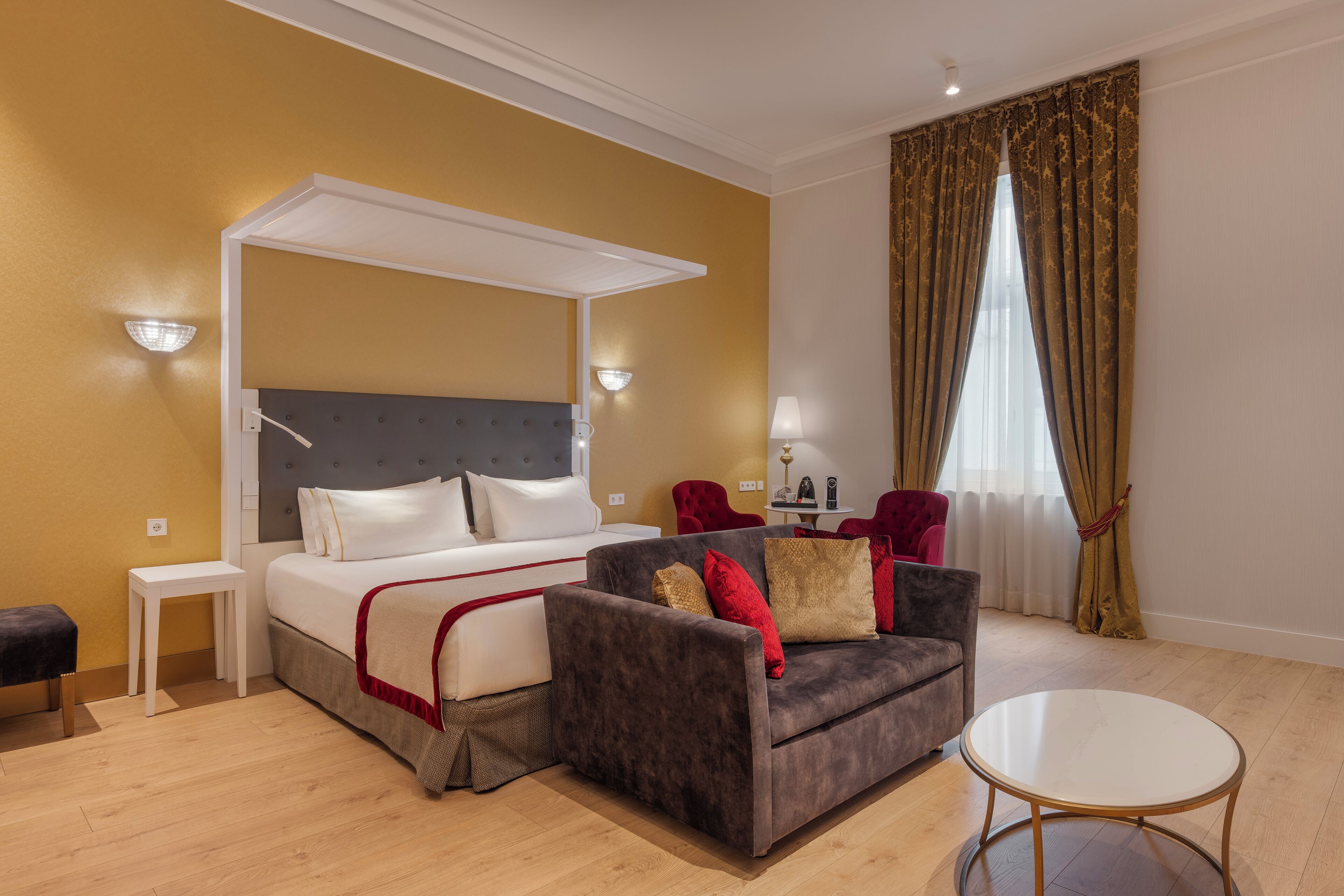 A hotel room with a bed, a sofa, a small table, and a round coffee table.