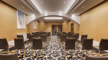 A conference room with rows of chairs, a patterned carpet, and a skylight ceiling.