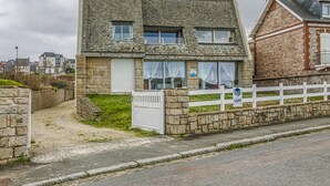 Une maison en pierre avec une clôture blanche, une allée bordée de portails et un panneau indiquant qu’il s’agit d’un chemin privé.