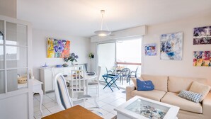 A modern living room with a sofa, coffee table, and dining area with chairs and a table. - La Lagune - Appartement vue mer (Pléneuf-Val-André)