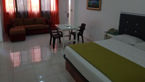 A hotel room with a bed, a desk, a chair, a sofa, and a painting on the wall. - Quiet and comfortable apartment in the center (Santo Domingo)