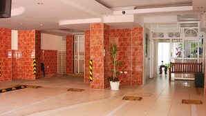 A spacious lobby with red-tiled walls, a potted plant, and a bench. - Quiet and comfortable apartment in the center (Santo Domingo)