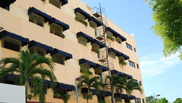 A multi-story hotel with balconies, a central stairwell, and outdoor plants. - Quiet and comfortable apartment in the center (Santo Domingo)