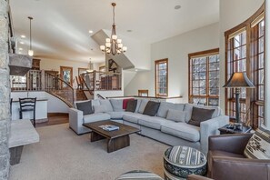 A spacious living area with a large sectional sofa, a coffee table, and a fireplace. - Base Camp 490 Private Hot Tub (Winter Park)