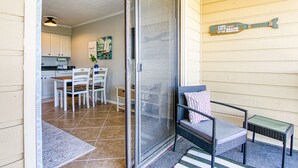 A covered patio with a sliding glass door leading to a dining area with white chairs and a table.