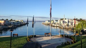 A waterfront marina with several flags, a docked boat, and a row of houses.