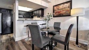 Een moderne keuken met donkere kastjes, een eethoek met vier stoelen, een ronde tafel en een kroonluchter.