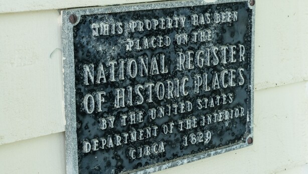 A plaque on a building wall stating the property is on the National Register of Historic Places. - Breakwater Estate… perfect for Large Group Getaways! (Mattituck)