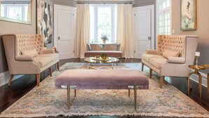 A spacious living room with a large chandelier, two armchairs, a coffee table, and a patterned rug. - Breakwater Estate… perfect for Large Group Getaways! (Mattituck)