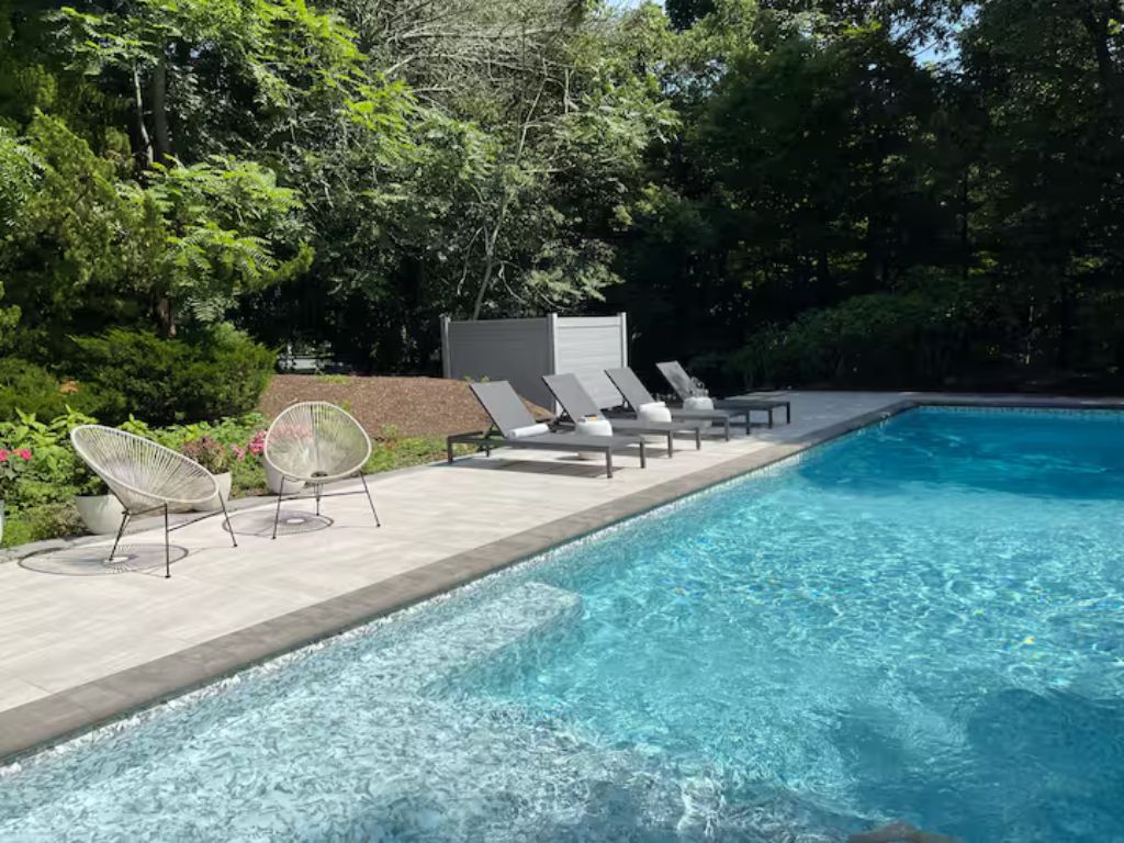 A swimming pool with lounge chairs and a small structure, surrounded by greenery.