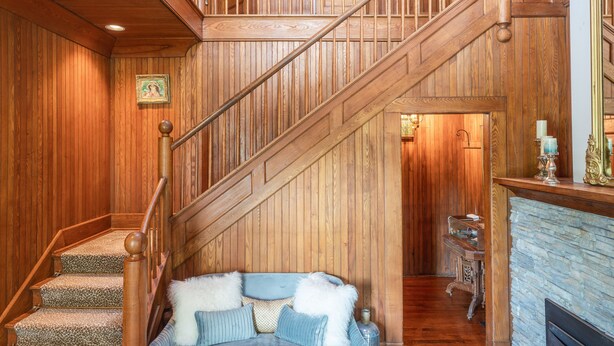 A wooden interior with a staircase, a blue sofa, and a fireplace. - Breakwater Estate… perfect for Large Group Getaways! (Mattituck)