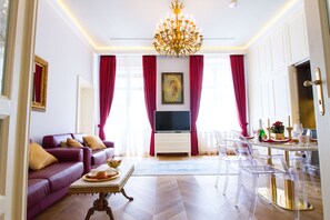 Una sala de estar con sofá, televisor, mesa de comedor, sillas y una araña.