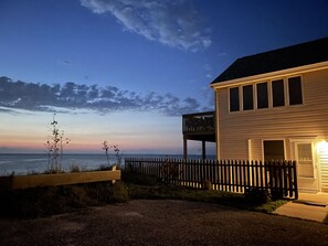 Ett hus vid kusten med en träveranda och en balkong med utsikt över havet.