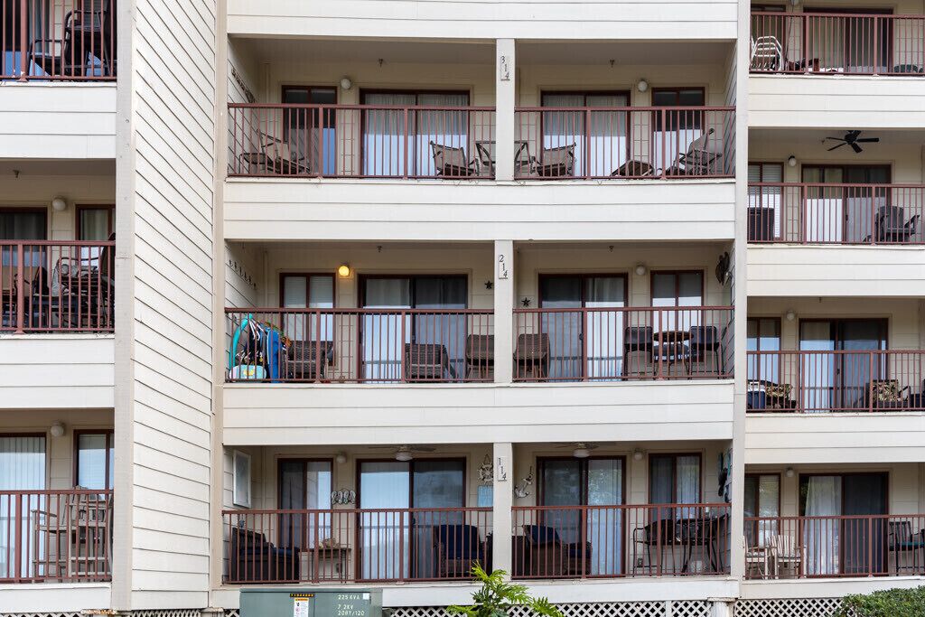A multi-story building with balconies, each with metal railings and outdoor furniture.