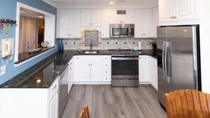 A modern kitchen with white cabinets, a stainless steel refrigerator, a microwave, and a stove. - Balcony overlooks BEAUTIFUL OCEAN VIEW, just steps away from sand! (Hilton Head Island)