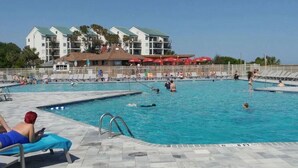 A swimming pool with multiple lanes, surrounded by lounge chairs and umbrellas. - Balcony overlooks BEAUTIFUL OCEAN VIEW, just steps away from sand! (Hilton Head Island)