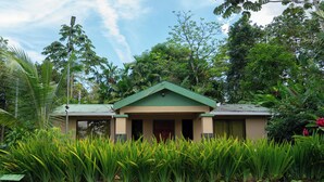 A building with a green roof and beige walls, surrounded by lush tropical vegetation. - Ceibo Arenal Home (La Fortuna)