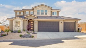 A two-story house with a stone facade, a dark garage door, and a well-maintained front yard with rocks and plants. - Paseos 1101, Private Hot Tub, Outdoor Games & Shared Pickleball Courts! (Washington)