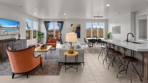 A modern living room with a sofa, coffee table, and a TV displaying a pool view. - Paseos 1101, Private Hot Tub, Outdoor Games & Shared Pickleball Courts! (Washington)