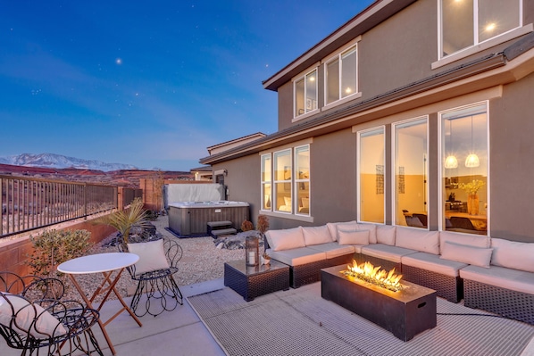 A rooftop patio with a fire pit, outdoor seating, and a hot tub.