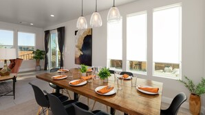 A dining area with a wooden table set for four, surrounded by black chairs. There are three pendant lights hanging above the table. - Paseos 1101, Private Hot Tub, Outdoor Games & Shared Pickleball Courts! (Washington)