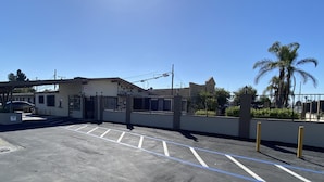 A parking lot with marked spaces, a gated entrance, and a building labeled "OFFICE" in the background. - Starlite Motel (Stanton)