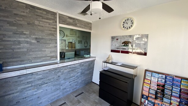 A reception area with a stone wall, a ceiling fan, a clock, and a wall with travel brochures. - Starlite Motel (Stanton)