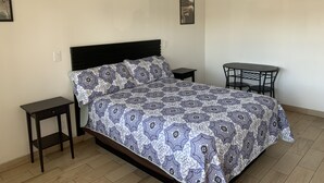 A bedroom with a bed, a small table, and a chair. - Starlite Motel (Stanton)