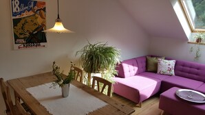 A cozy room with a wooden dining table, purple sofa, and a hanging light fixture. - Above the roofs of Lana - Green Apartment - via Dolce Vita (Lana)