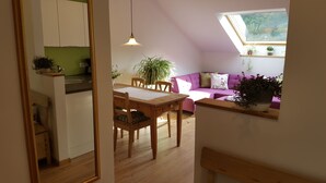 A cozy living area with a wooden dining table, a purple sofa, and a skylight above. - Above the roofs of Lana - Green Apartment - via Dolce Vita (Lana)