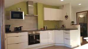 A modern kitchen with white cabinets, a built-in oven, a microwave, and a coffee maker. - Above the roofs of Lana - Green Apartment - via Dolce Vita (Lana)