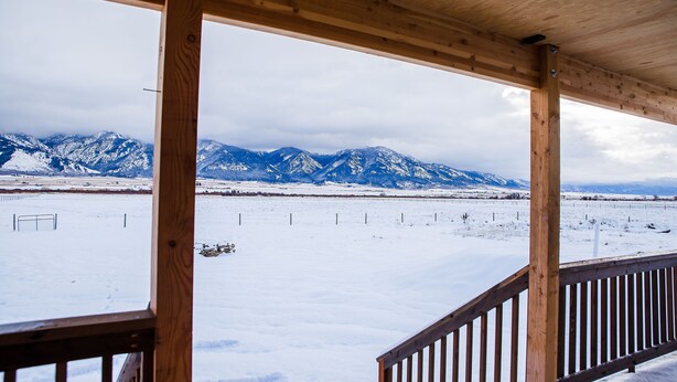 Una terraza de madera con vistas a montañas nevadas.