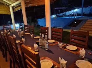 An outdoor dining area with a pool in the background.