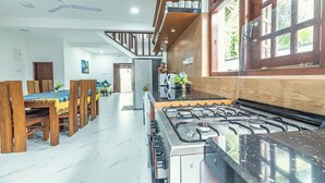 A modern kitchen with a gas stove, wooden dining table, and a ceiling fan. - Villa Talpe 5 Bedrooms & Massage Pool (Unawatuna)