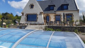 Uma casa grande com telhado íngreme, várias janelas e fachada de pedra.