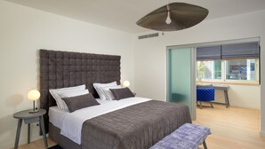 Ein modernes Schlafzimmer mit einem großen Bett, Nachttischen, einer Bank und einem Fenster mit Blick.