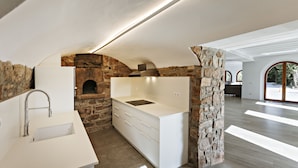 A modern kitchen with a stone arch, a built-in oven, and a white countertop. - masoveria la boba (Vilanova de la Aguda)