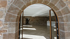 A stone archway leading to a room with a wooden floor and a white ceiling. - masoveria la boba (Vilanova de la Aguda)