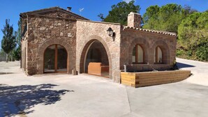 A stone building with arched windows and a chimney. - masoveria la boba (Vilanova de la Aguda)