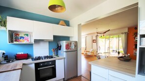 Une cuisine avec des meubles blancs, un réfrigérateur, une cuisinière et un four à micro-ondes.