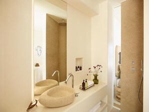 A bathroom with two stone sinks, a large mirror, and a shower. - White Pebble Suites (Milos)
