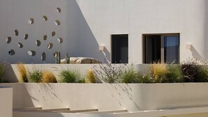 A modern building with a unique facade featuring circular cutouts, a flat roof, and a minimalist design. - White Pebble Suites (Milos)