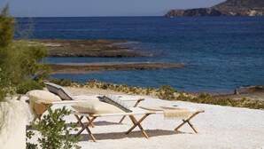 A beachside lounge with sun loungers and a view of the sea. - White Pebble Suites (Milos)