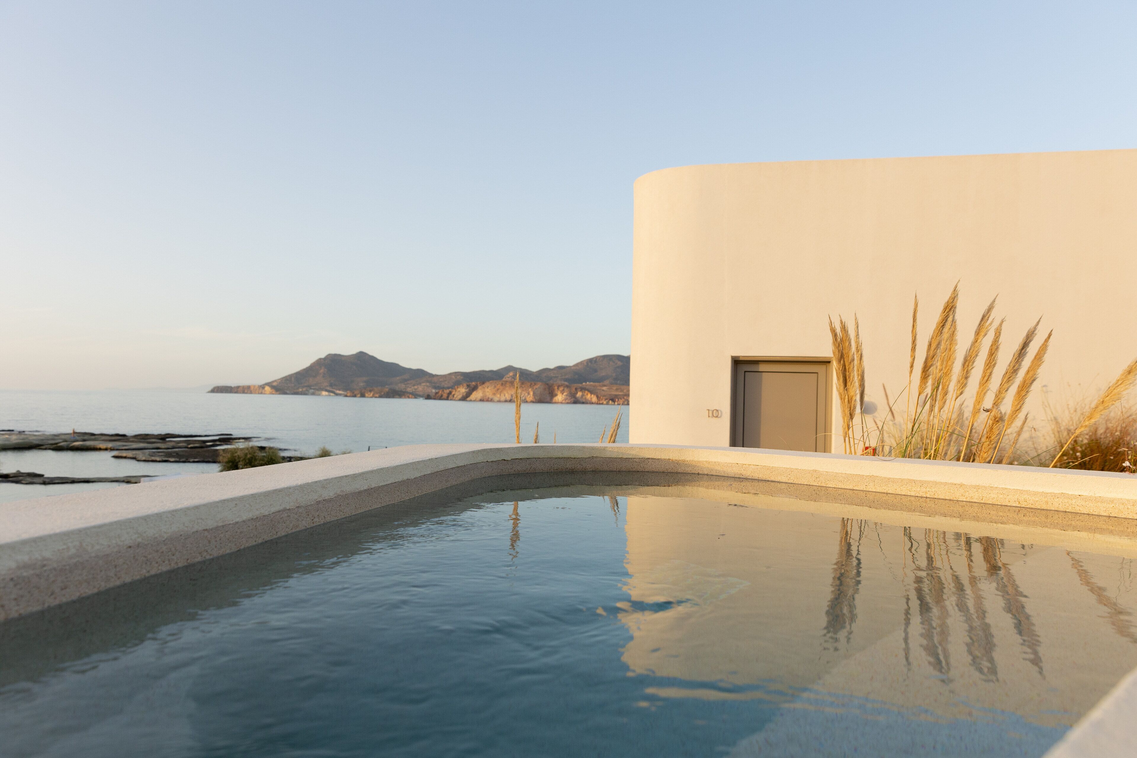 A modern pool with a clear view of the sea and mountains in the background.