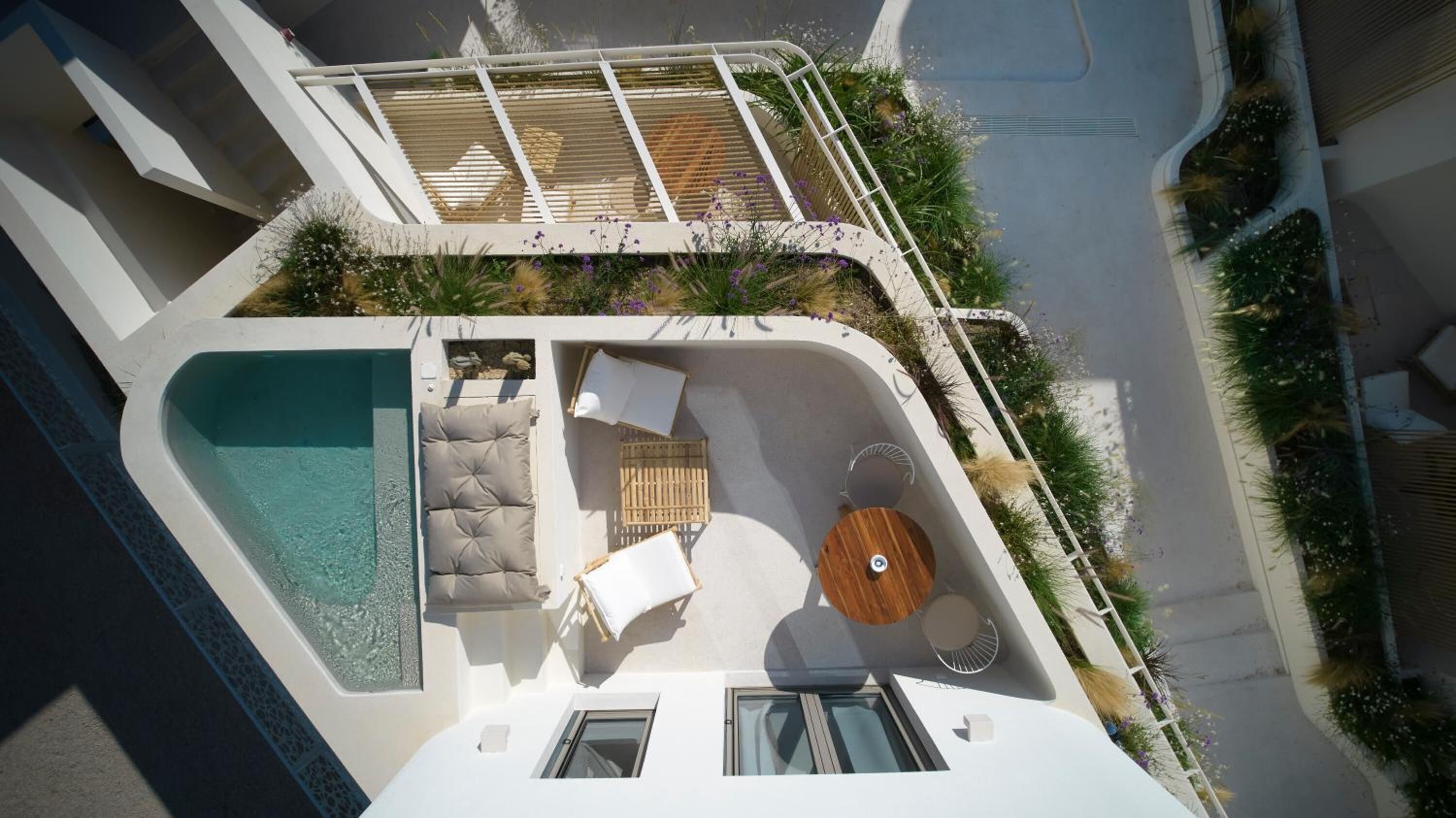 Area piscina sul tetto con una poltrona prendisole, un tavolino rotondo e un angolo salotto.