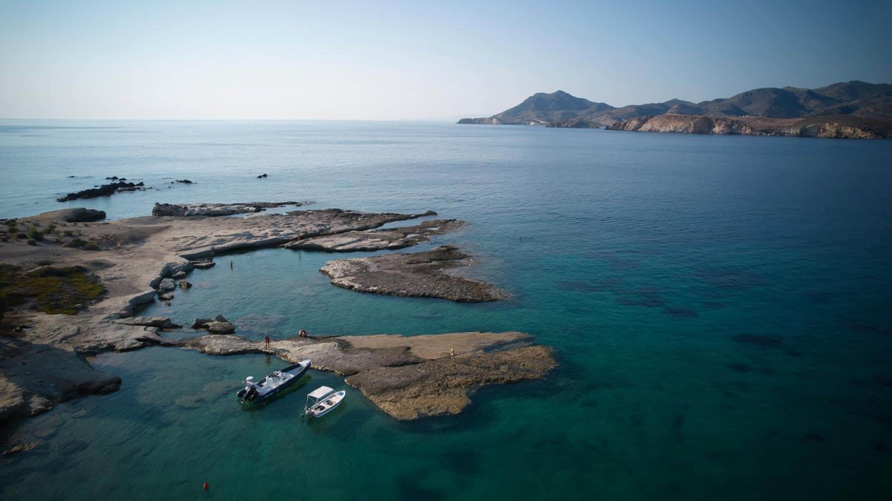 An aerial view of a coastal area with rocky formations and clear turquoise waters.
