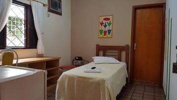 Cozy retreat with a single bed, bedside table, and chair, plus a small table and chair near the window.