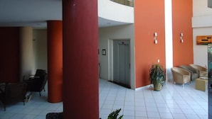 A spacious lobby with a high ceiling, a central staircase, and a seating area with chairs. - Hotel Colorado (Rio Verde)