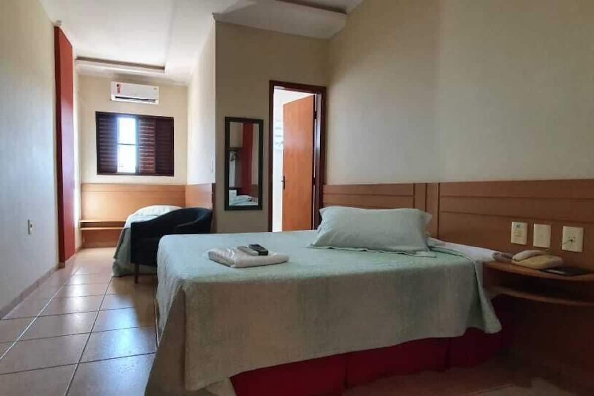 Une chambre d’hôtel avec un lit, un bureau, une chaise et une fenêtre.